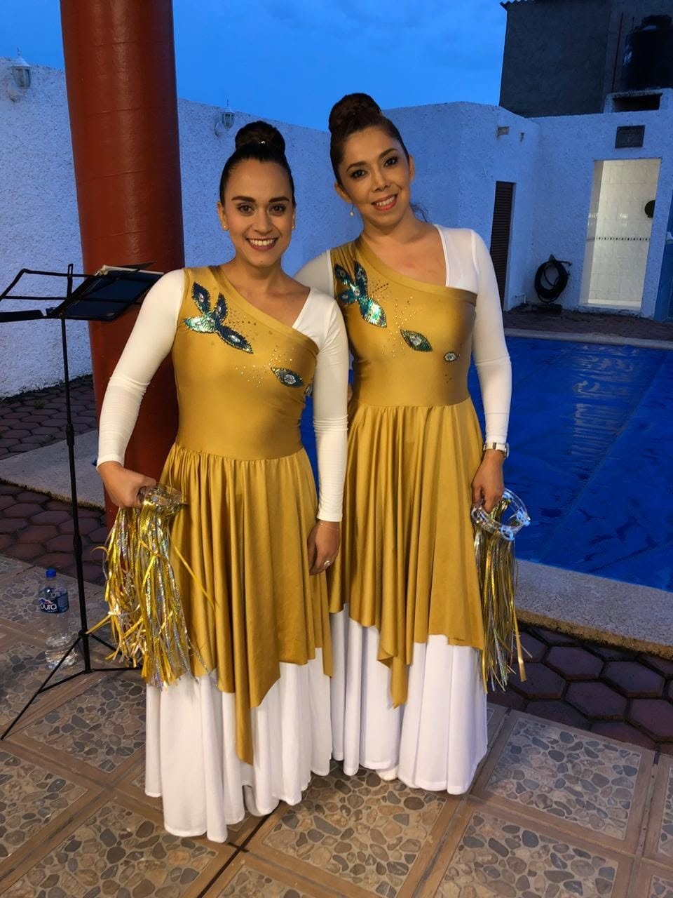Two people wearing coordinated gold and white performance dresses
