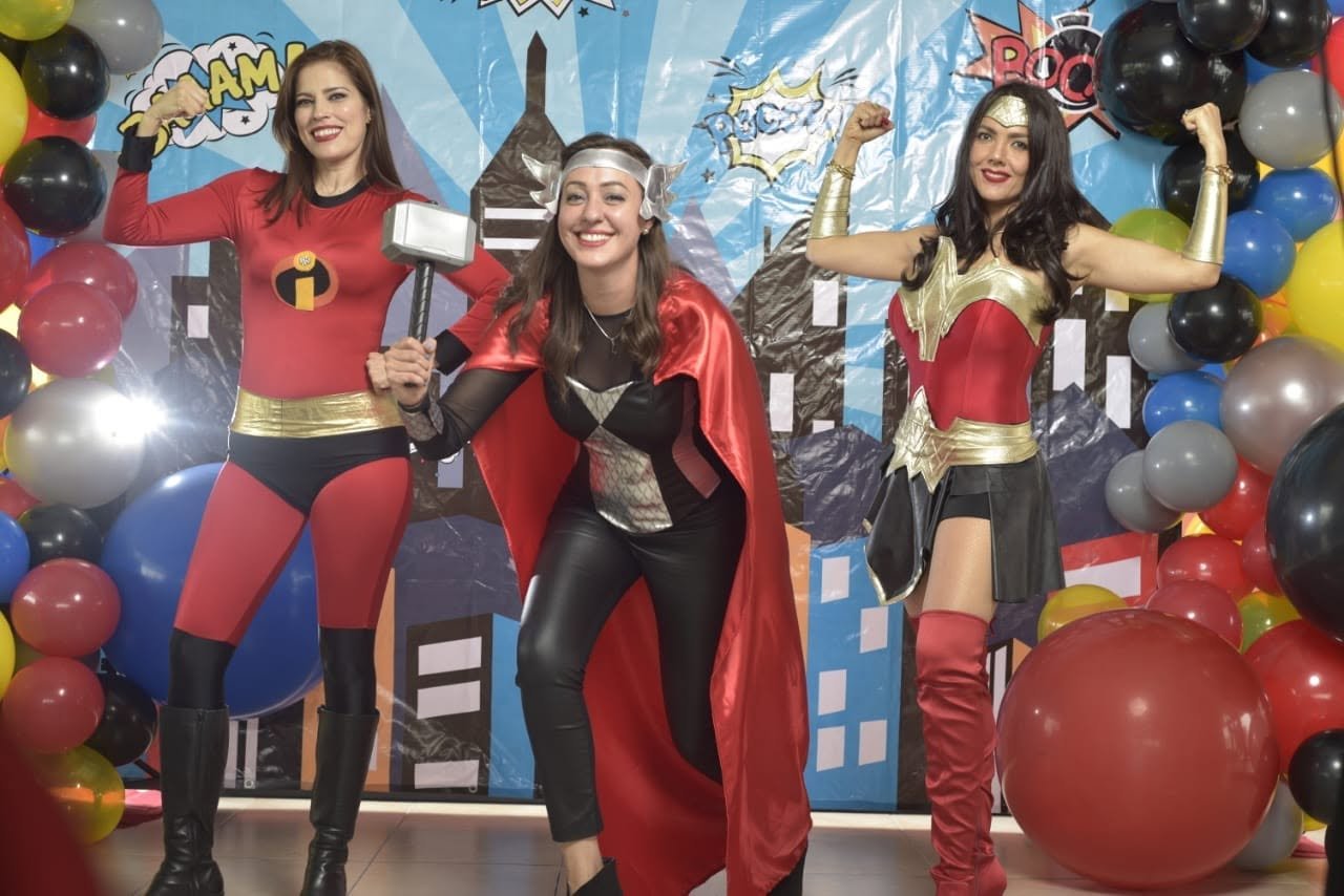 Three women wearing custom superhero costumes